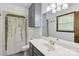 Bathroom featuring a single sink vanity, light fixture, shower/tub combo, and window at 119 Legacy Ln, Harmony, NC 28634