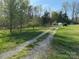 Gravel driveway leading through a grassy landscape with lush trees at 196 Cindy Ln, Kings Mountain, NC 28086