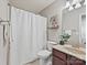 The full bathroom with a neutral colored shower curtain, granite countertops, and wooden cabinets at 2268 Kensington Station Pkwy, Charlotte, NC 28210