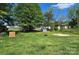A backyard featuring green grass and mature trees and other homes and garages in the background at 2607 Lowell Rd, Gastonia, NC 28054