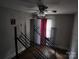Bedroom with ceiling fan, a window covered by a red curtain, hardwood floors, and walls needing cleaning at 2607 Lowell Rd, Gastonia, NC 28054