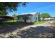 Rear view of a home featuring an attached carport, driveway, green lawn, and mature trees offering shade at 2607 Lowell Rd, Gastonia, NC 28054