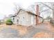 Side exterior view of home with brick foundation, tan siding, chimney, and gravel driveway at 2616 Holton Ave, Charlotte, NC 28208