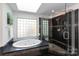 The bright bathroom featuring a glass block window, jacuzzi tub and glass shower at 3010 Lakewood Edge Dr, Charlotte, NC 28269