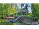 Lakefront home featuring a private dock, boat lift, and lakeside views surrounded by mature trees and lush landscaping at 3915 Chevlot Hills Rd, Sherrills Ford, NC 28673