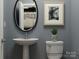 Stylish powder room featuring a pedestal sink, oval mirror, and framed artwork at 4222 Skyboat Cir, Fort Mill, SC 29715