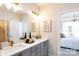 Bright bathroom features double vanity, framed mirrors, gray cabinets, and view into main bedroom at 4825 Reason Ct # 73, Harrisburg, NC 28075