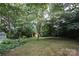 Backyard with green lawn and small shed nestled amongst mature shade trees at 516 Northgate Ave, Charlotte, NC 28209