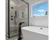Bright bathroom showcasing a soaking tub and glass-enclosed shower with window view at 545 Morrison Farm Rd, Troutman, NC 28166