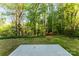 Flat backyard surrounded by a natural border of lush green trees, offering privacy and a serene outdoor space at 551 Belfast Dr, Gastonia, NC 28052
