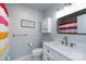 Bright bathroom with white vanity, hexagon tile floor, and colorful striped shower curtain at 8210 Lantana Dr, Denver, NC 28037