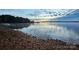 Picturesque lake view featuring calm water reflecting the sunset and a rocky beach foreground at 8210 Lantana Dr, Denver, NC 28037