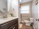 Well-lit bathroom features a dark vanity, a round mirror, and accessible toilet at 905 Mount Olivet Rd, Kannapolis, NC 28083