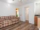 A plaid sofa sits in a room that features wood floors, access to the bathroom and another room at 905 Mount Olivet Rd, Kannapolis, NC 28083