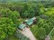 Stunning aerial view of a log home nestled among lush trees with a green metal roof and a spacious driveway at 10583 Earnhardt Lake Rd, Davidson, NC 28036