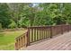 Deck with stairway leads to a lush, grassy backyard bordered by a wooden fence and mature trees at 10583 Earnhardt Lake Rd, Davidson, NC 28036