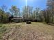 A ranch style home sits on a lot with tall trees and sloping front yard at 10625 Cool Springs Rd, Woodleaf, NC 27054