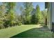 Spacious, grassy backyard framed by mature trees, with a garden bed along the side of the home at 1306 Kings Bottom Dr, Fort Mill, SC 29715