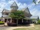 Exterior view of the brick clubhouse featuring a prominent tower, covered porch, and manicured landscaping at 1306 Kings Bottom Dr, Fort Mill, SC 29715