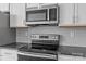 Modern kitchen with stainless steel appliances, gray backsplash, and granite countertops at 133 Capital Ave # B, Mooresville, NC 28117