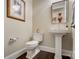 Powder room featuring pedestal sink, white toilet, decorative art, and dark hardwood floors at 17315 Langston Dr, Charlotte, NC 28278