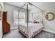 Cozy bedroom with four-poster bed, neutral walls, carpet, and window with blinds for natural light at 17315 Langston Dr, Charlotte, NC 28278