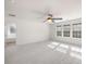 A spacious room with neutral colored carpet, three large windows, and a ceiling fan at 17413 Caddy Ct, Charlotte, NC 28278
