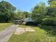 Quaint, overgrown exterior with an attached carport, concrete front, and mature trees, perfect for renovation at 191 S Main St, Richburg, SC 29729