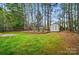 Expansive backyard featuring a storage shed, lush lawn, tall trees and defined by a retaining wall at 212 Kilborne Rd, Mooresville, NC 28117