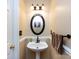 Charming half-bath features pedestal sink, dark fixtures, and decorative oval mirror at 2316 Highland Park Dr, Charlotte, NC 28269