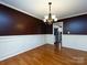 Well-lit dining room boasts hardwood floors, stylish wainscoting, and an elegant chandelier at 2316 Highland Park Dr, Charlotte, NC 28269