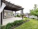 Covered patio with stylish pergola, adjacent to a lush lawn and manicured garden at 2316 Highland Park Dr, Charlotte, NC 28269