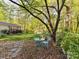 Serene backyard patio area with a quaint table and chairs, surrounded by lush greenery and mature trees at 3232 Kale Ln, Matthews, NC 28105