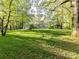 Expansive backyard with lush green grass, mature trees, and a charming brick home in the distance at 3232 Kale Ln, Matthews, NC 28105