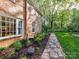 Exterior view of a brick house with lush landscaping and a stone path at 3232 Kale Ln, Matthews, NC 28105