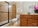 Well-lit bathroom features tiled shower with glass doors, toilet, and a wooden vanity with sink at 404 Brookridge Dr, Mount Holly, NC 28120