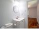 Bright bathroom features a round mirror, white vanity, and an open doorway to a room with hardwood floors at 4925 Seacroft Rd, Charlotte, NC 28210