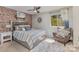 Comfortable bedroom with a brick accent wall, ceiling fan, soft lighting, and a cozy chair at 7324 Pebblestone Dr # E, Charlotte, NC 28212