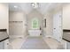 Bathroom featuring a soaking tub, neutral tile flooring, black hardware, and a vaulted ceiling at 7600 Brookmont Ln, Waxhaw, NC 28173