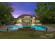 Stunning backyard view at dusk showcasing a large in-ground pool with a patio and screened porch at 7600 Brookmont Ln, Waxhaw, NC 28173