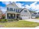Charming two-story home with a stone-accented porch, three-car garage, and well-manicured lawn at 8419 Everwood Ave, Huntersville, NC 28078