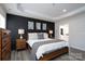 Stylish main bedroom features a tray ceiling, hardwood accent wall, neutral bedding, and ensuite access at 8419 Everwood Ave, Huntersville, NC 28078