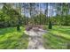 Backyard with a firepit and stone bench seating, surrounded by lush landscaping, creating a serene retreat at 10416 Glenmac Rd, Charlotte, NC 28215