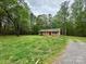Charming brick home with a red door, enveloped by mature trees and a vast green lawn at 181 Canipe Rd, Dallas, NC 28034