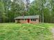 A quaint brick house with a red front door is framed by tall trees and a well-kept lawn at 181 Canipe Rd, Dallas, NC 28034