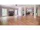Open-concept living room with stone fireplace, wood floors, and seamless flow to the modern kitchen at 1811 Robbins Meadows Dr, Waxhaw, NC 28173
