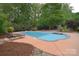 A beautiful backyard pool featuring lounge chairs, manicured landscaping, and wooden pool houses at 1811 Robbins Meadows Dr, Waxhaw, NC 28173