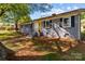 Gray brick home featuring black shutters, landscaping, and a welcoming entryway under a canopy of trees at 1860 Rosemont St, Salisbury, NC 28144