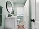 Well-lit bathroom with white cabinets, mosaic tile floor, and a large round mirror at 1927 S Wendover Rd, Charlotte, NC 28211