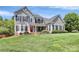 Charming two-story home boasts a well-manicured lawn, complemented by black shutters and a striking red front door at 1930 Southridge Dr, Belmont, NC 28012